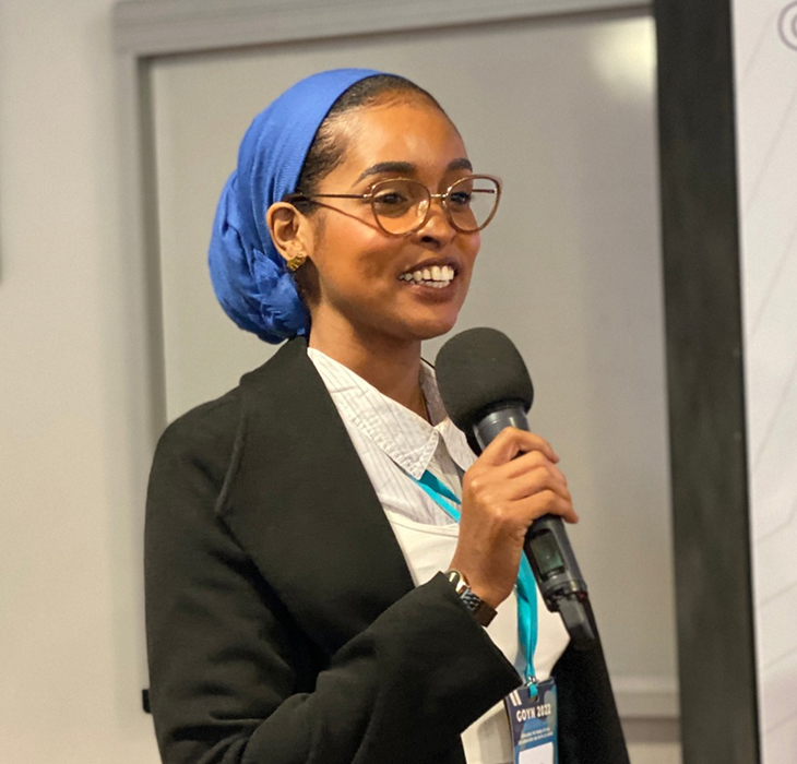 Young woman holds the microphone and addresses those in attendance